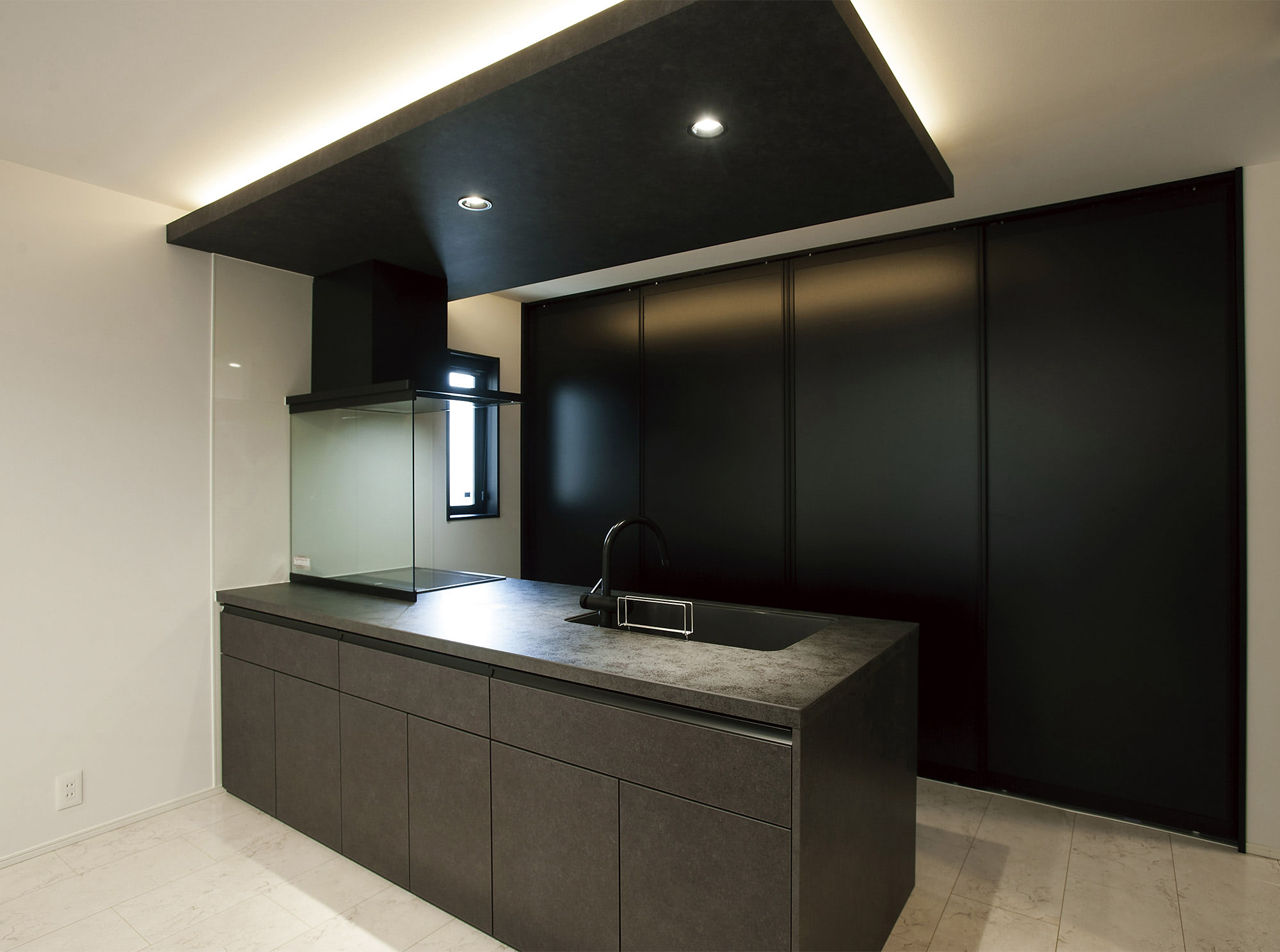 キッチンは、冷蔵庫や家電も収められるブラックの背面収納を採用しています。
